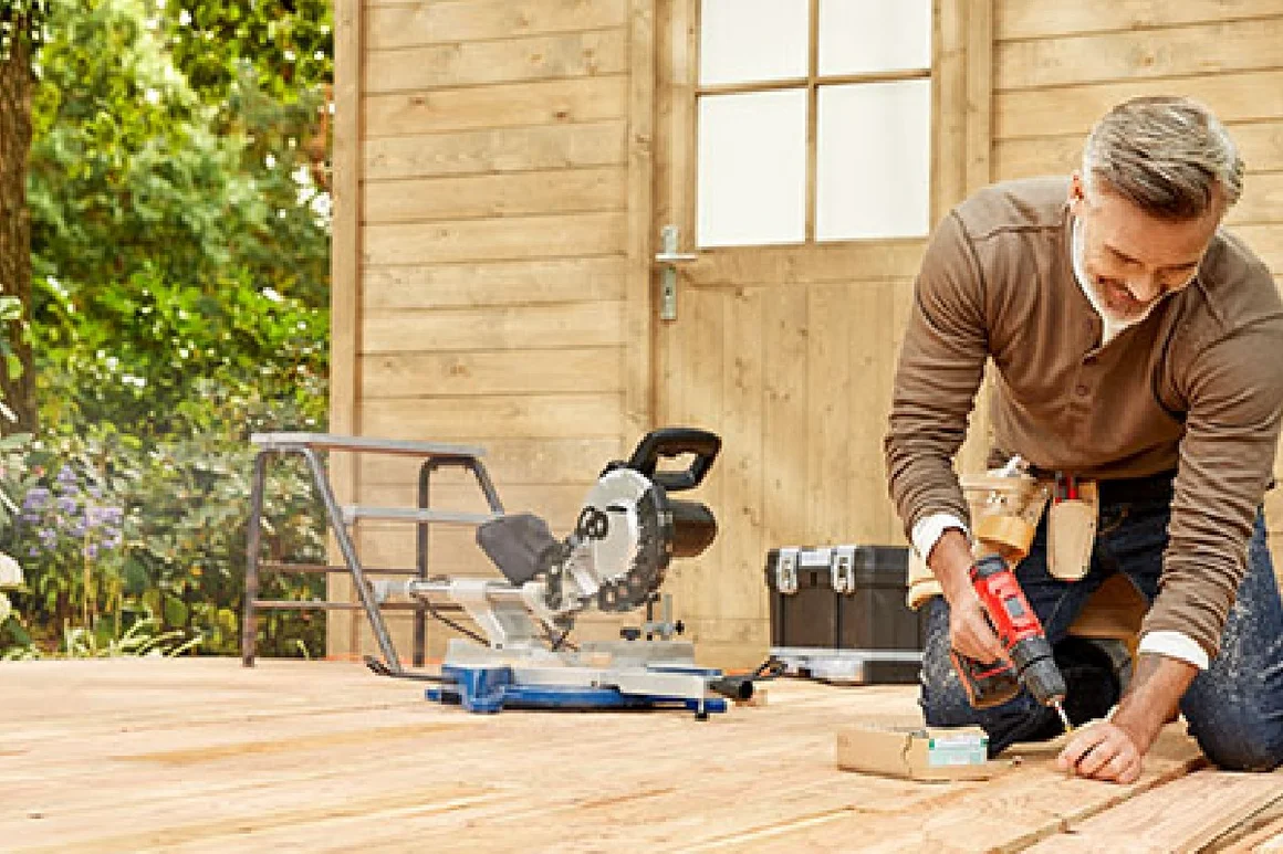 Person baut Holzterrasse mit Akkuschrauber